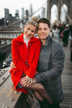 a man and woman standing next to each other on a bridge