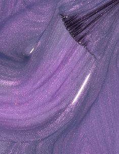 a purple brush is laying on top of some shiny material that looks like it has been dyed