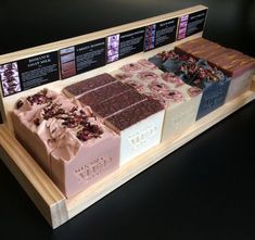 an assortment of different types of chocolates on display in a wooden tray with information