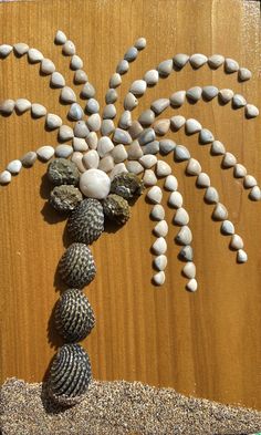 a sculpture made out of rocks and shells on a wooden surface with the shape of a palm tree