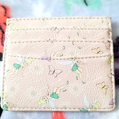 a pink wallet with tinkerbells on it sitting on top of a table