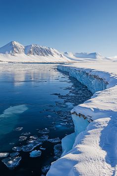 the ice is melting on the water and there are mountains in the background