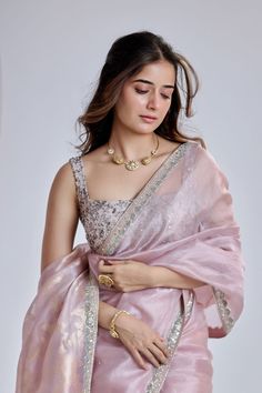 a woman in a pink sari with gold jewelry on her neck and hands behind her back