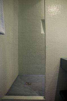 a bathroom with a white tiled shower stall and toilet paper on the wall next to it