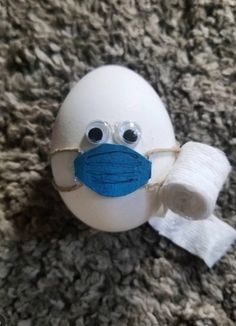 an egg with a face mask and bandage around its neck on the carpet, looking like it has been wrapped in bandages