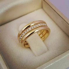 two gold wedding bands in a box with diamonds on the inside and outside of them