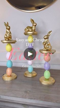 three gold bunny figurines sitting on top of each other in front of a mirror