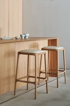 two stools in front of a counter with bowls on it