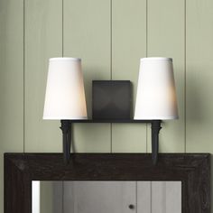 two lamps sitting on top of a mirror in front of a wall mounted light fixture