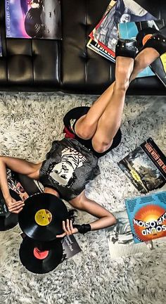 a man laying on the floor next to a woman holding a record and some books