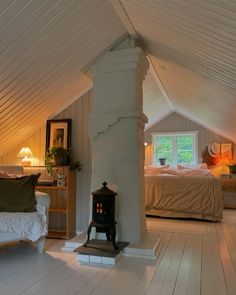 an attic bedroom with wood floors and white walls, along with a bed in the corner