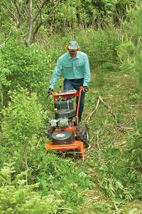 a man is mowing the grass with an orange lawnmower in his hand