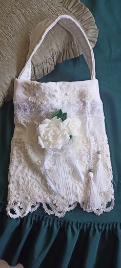 a white purse sitting on top of a bed next to a green blanket and pillow