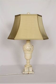 a white lamp with a beige shade on it's base and a cord plugged in