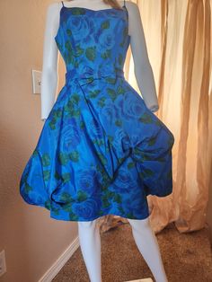 PLEASE READ ENTIRE DESCRIPTION ....Gorgeous 60's blue evening dress. Large blue roses with dark, muted green leaves. Crisp, shiny material, possibly polyester, with fully lined purple satin lining. Back metal zipper with no pockets. The poofy part of the dress has tulle fabric to give it body. It is covered with the lining. In very good, previously worn, vintage condition.  No stains or holes and it looks to me that all seams are tight with the exception of the bow. It is loose on one side, just Marilyn Monroe Blue Dress Polka Dots, Blue 70s Dress, Blue 60s Dress, Blue 1950s Style Cotton Vintage Dress, 1960s Brocade Dress, Blue Evening Dress, Muted Green, Blue Evening Dresses, Purple Satin