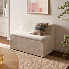 a living room with a couch, rug and potted plant on the side table