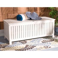 a white bench sitting on top of a rug in front of a brick wall next to a potted plant