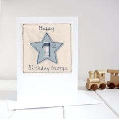 a birthday card with a blue star on it and wooden train cars in the background