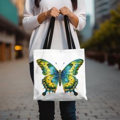 This tote bag with a big butterfly modern print is the perfect accessory for nature lovers and style enthusiasts alike. Featuring a bold and vibrant butterfly design, this tote adds a touch of whimsy and elegance to any outfit. Whether you're using it for groceries, books, or as an everyday carry-all, this reusable bag is as practical as it is eye-catching. Made from durable materials, it's designed to withstand daily use while helping you reduce waste. A perfect gift for butterfly lovers or those who appreciate unique, nature-inspired designs, this modern butterfly tote is sure to become a favorite accessory! Available in 3 sizes to add both functionality and style, these custom-printed tote bags come with multiple handle colors to match your designs. Made with spun polyester, these bags Hot Pink Bag With Yellow Butterfly, Butterfly Print Bag For Gift, Hot Pink Bag With Butterfly, Butterfly Purse Handbags, Everyday Butterfly Print Tote Bag, Big Butterfly, Rectangular Travel Bag With Butterfly Print, Nature Inspired Design, Carry All Bag