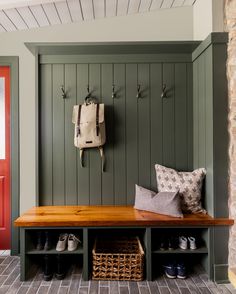 a wooden bench sitting next to a wall with shoes on it and a bag hanging from the back