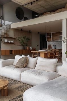 a living room filled with white couches next to a wooden coffee table and stairs