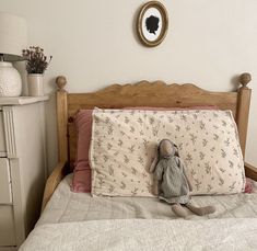 a stuffed animal sitting on top of a bed next to a night stand and dresser