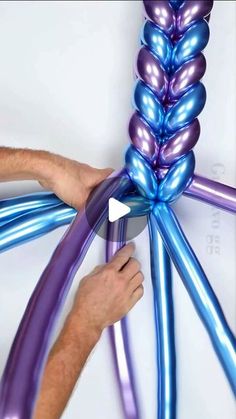 a man is holding balloons in the shape of an oar with purple and blue colors