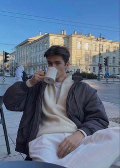 a man sitting at a table drinking from a cup