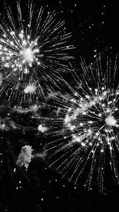 black and white photograph of fireworks in the night sky with stars on it's side