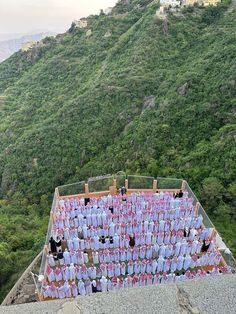 a group of people standing on top of a roof next to a lush green hillside