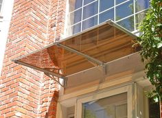 an awning on the side of a brick building next to a tree and window