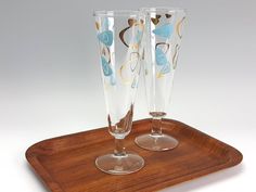 two wine glasses sitting on top of a wooden tray