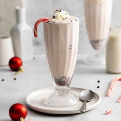 two glasses filled with milkshakes and candy canes on a plate next to peppermint sticks