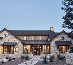 a large stone house with two story windows and a walkway leading to the front door