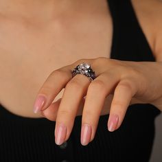 A cool black bat ring boasts a central, dazzling round gemstone, with bat images sculpted on both sides, infusing a touch of the macabre and the enchanting. Surrounding the main stone are sparkling purple and white stones, creating a striking and elegant contrast. Crafted from polished silver metal, the two tone fashion black ring features intricately carved black bat wing decorations, thereby enhancing its mystical charm. Inside, a spider's web-like hollowed-out lining lends an air of whimsy. It's a perfect fusion of sophistication, mystery, and allure, making it a standout accessory for any occasion.Carat Weight: 3.5 ctStone Size: 8 mmStone Type: Jeulia® StoneNumber of Stones: 1 Stone Color: Diamond WhiteStone Shape: RoundCarat Weight: 2.254 ctStone Size: 1.5,1,5*7 mmStone Type: Jeulia® Elegant Black Skull Ring For Halloween, Bat Images, Bat Ring, White Stones, Bat Wing, Black Ring, Black Bat, Fashion Black, Ring Sterling Silver