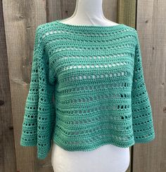 a green crocheted sweater on a mannequin