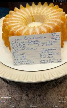 a white plate topped with a cake covered in fruit and writing on the top of it