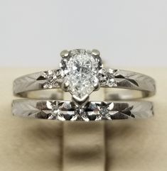 an engagement ring set with a pear shaped diamond in the center and side stones on each band