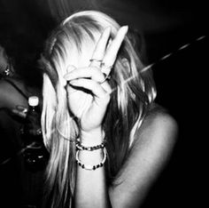 a woman making the v sign with her hand while sitting in front of a bar