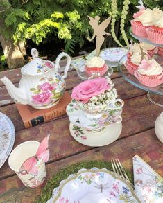 a table topped with cupcakes covered in frosting next to plates and cups