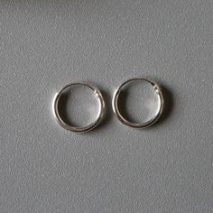 Delicate minimal sterling silver jewelry. Our products are made with 925 sterling silver and are hypoallergenic and nickel free! *Middle one in the picture ★ This listing is for a PAIR of hoops.  ★ Hoop dimensions 10mm outer diameter, 8mm inner diameter  1mm thickness ★ Material 925 sterling silver  Your earrings will come in a cute gift box! We will ship them out asap, shipping is fixed price for as many items as you want. Minimalist Silver Huggie Jewelry, Minimalist Nickel-free Silver Hoop Earrings, Simple Sterling Silver Round Jewelry, Silver Sterling Hoop Earrings With Simple Design, Simple Silver Round Earrings, Simple Hypoallergenic Jewelry, Silver Minimalist Hoop Earrings, Classic Hypoallergenic Sterling Silver Jewelry, Hypoallergenic Classic Sterling Silver Jewelry