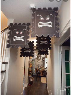 two black and white paper cut outs with faces on them hanging from the ceiling in a hallway