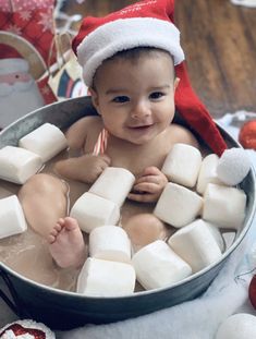 a baby in a tub with marshmallows and santa's hat on