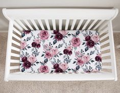 a white crib with pink and red flowers on it