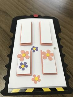 an open card with flowers on it sitting on a wooden table next to a pair of scissors