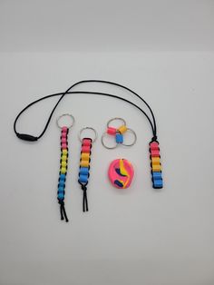 a group of different colored items on a white surface with black string and keychains