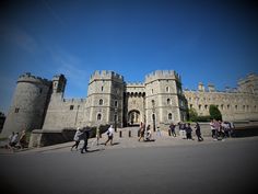 people are walking in front of an old castle