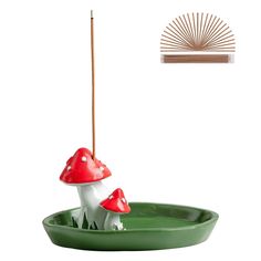 a green tray with two mushrooms on it and a bamboo stick sticking out of the top