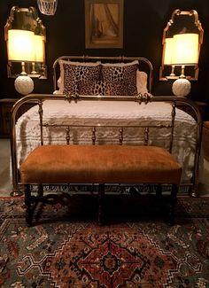 a leopard print bed with two lamps on either side and a bench in the middle