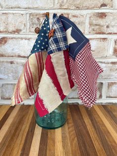 an american flag in a mason jar on a wooden table next to a brick wall